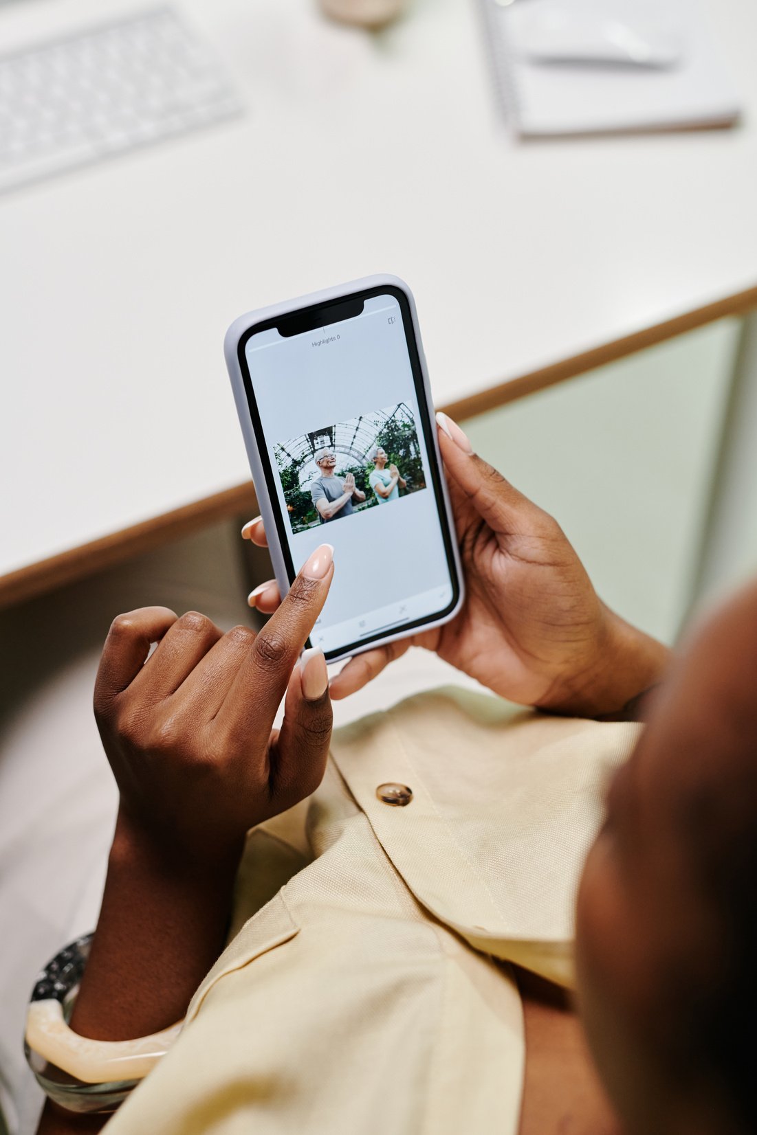 Photograph of a Person in a Beige Shirt Using a Cell Phone